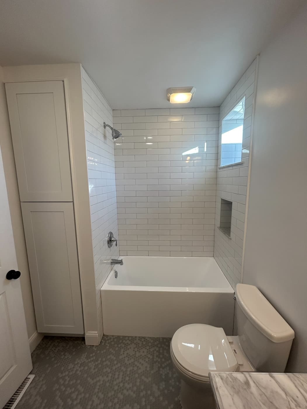 Remodeled bathroom with a white subway-tile surround and new tub