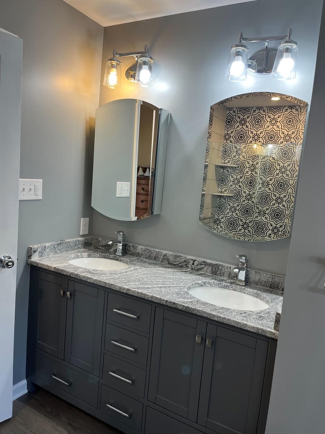Finished double vanity with arched mirrors and a tiled accent wall